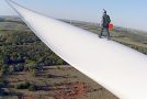 BASE jumper jumps off of a very tall wind turbine blade
