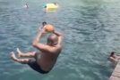 Man throws a ball high up in the air while diving in the pool